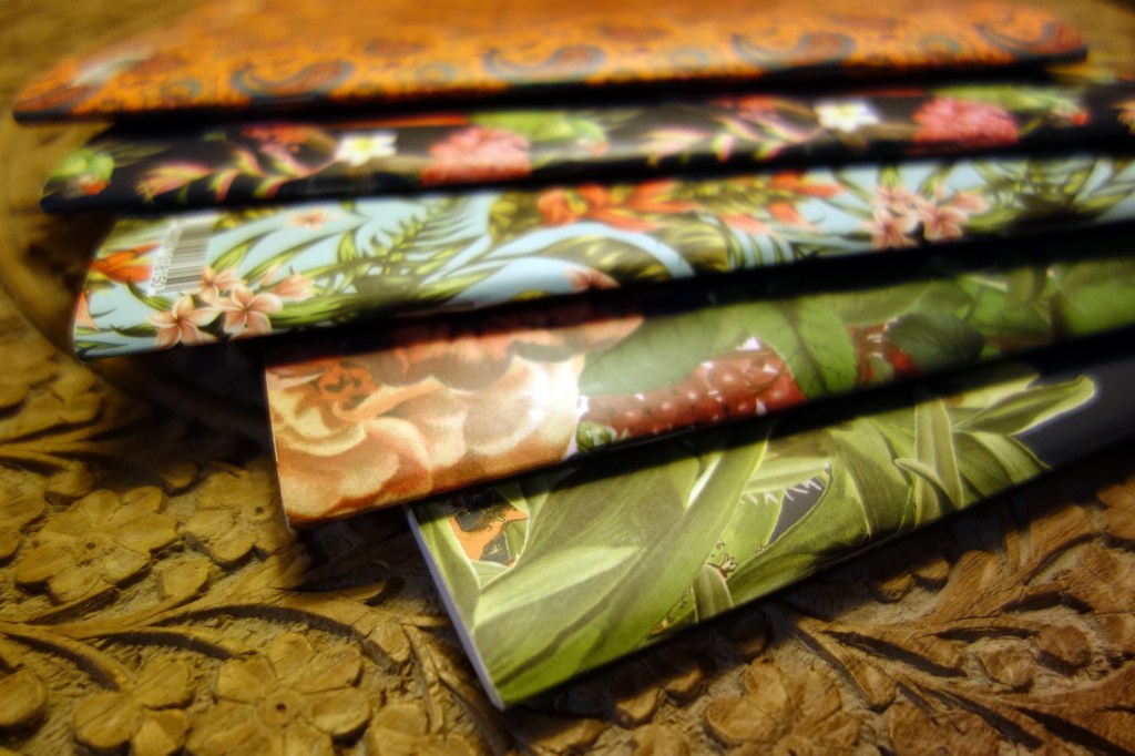 Ein Stapel bunter Notizbücher auf einem Holztisch.