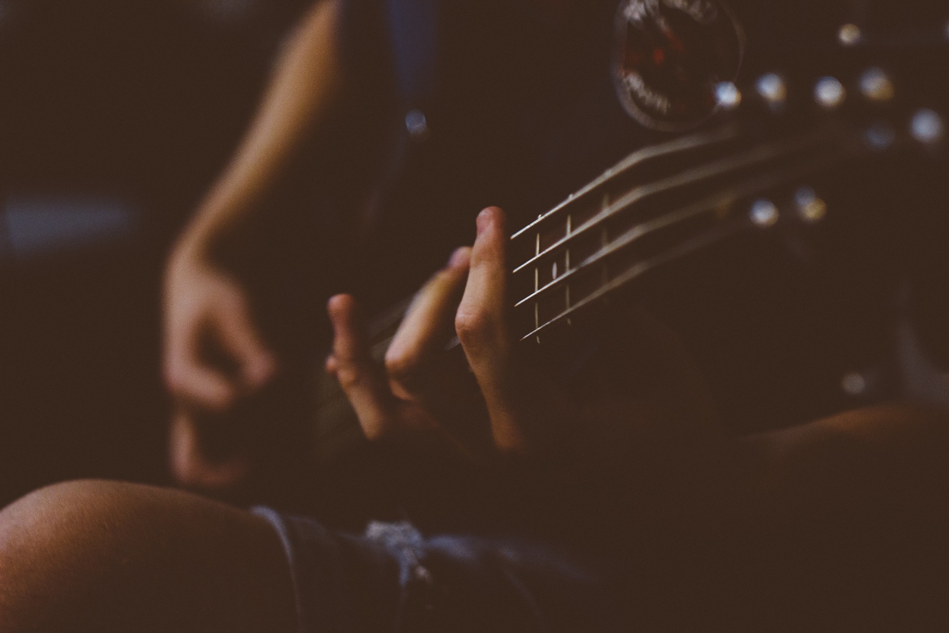 Frau mit Gitarre, Finger in Nahaufnahme, Hintergrund verschwommen (Bild: Pexels auf Pixabay)
