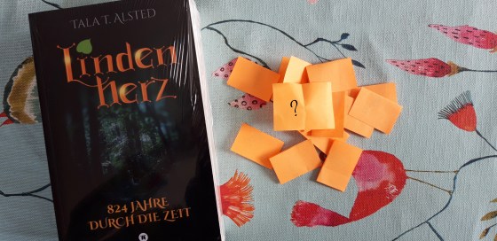 Taschenbuch "Lindenherz - 824 Jahre durch die Zeit" von Tala T. Alsted und ein Häufchen Los-Zettel daneben
