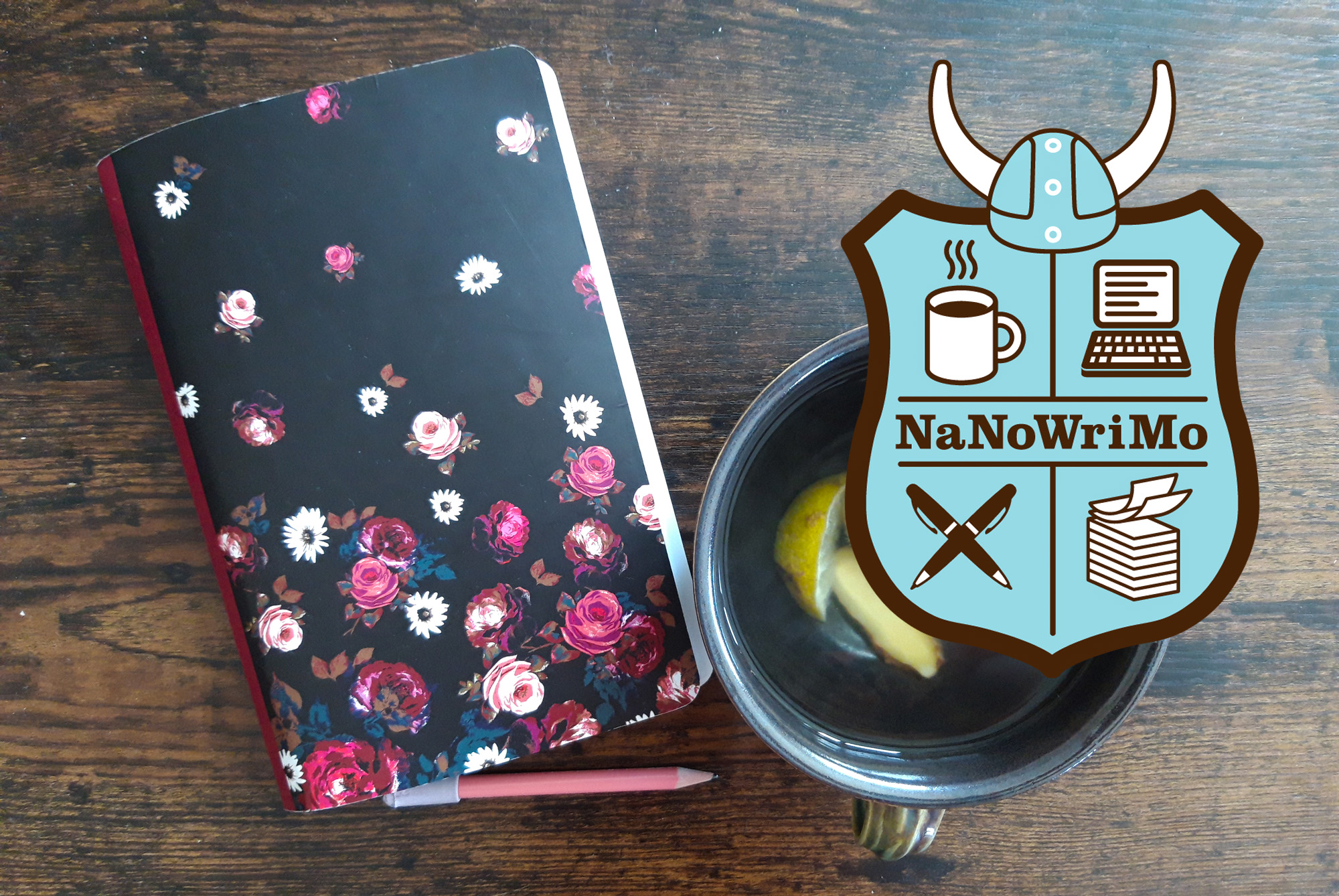 Notizbuch neben einer Tasse Tee und einem Bleistift zusammen mit dem Logo des NaNoWriMo