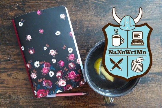 Notizbuch neben einer Tasse Tee und einem Bleistift zusammen mit dem Logo des NaNoWriMo