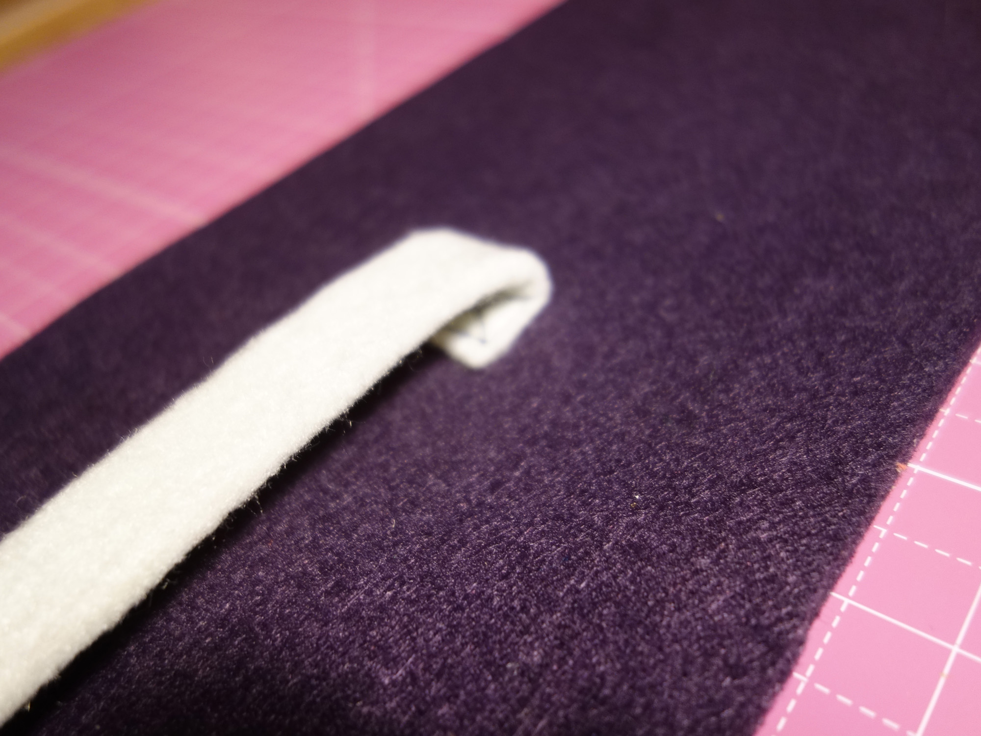 Das festgenähte Ende des Verschlussbands wird danach nach oben gebeugt, sodass eine Schlinge entsteht.