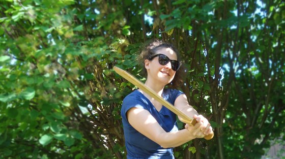 Autorin Tala T. Alsted mit einem Holzschwert vor Waldhintergrund