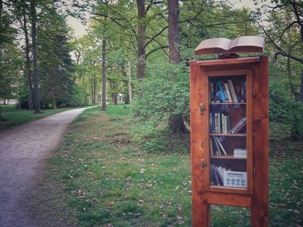 Bücherschrank in einem Park, Holzkasten mit geschnitzten Buch oben drauf