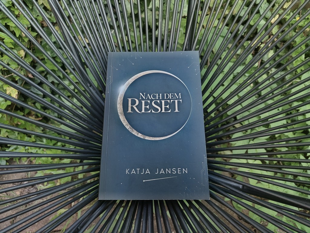 Das Buch "Nach dem Reset" liegt in einem Gartenstuhl